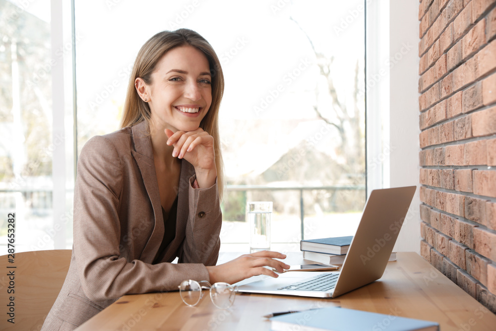 Young businesswoman using laptop at table in office Young businesswoman using laptop at table in office