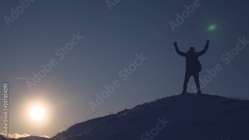 Mountaineer Journey to mountains in winter. Traveler climbs mountain peak. tourist stands on high snowy mountain, waves his hands and rejoices at victory at sunset. Alpenist travels hiking. © zoteva87
