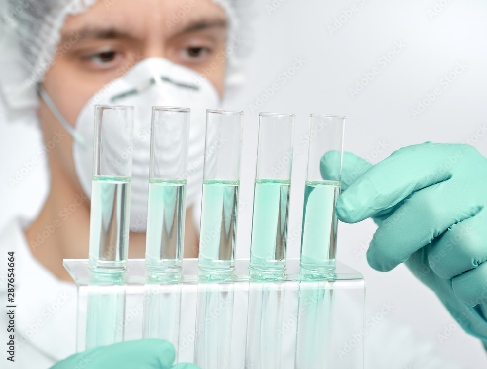 Keen scientist in protective wear with liquid samples Keen scientist in protective wear with liquid samples