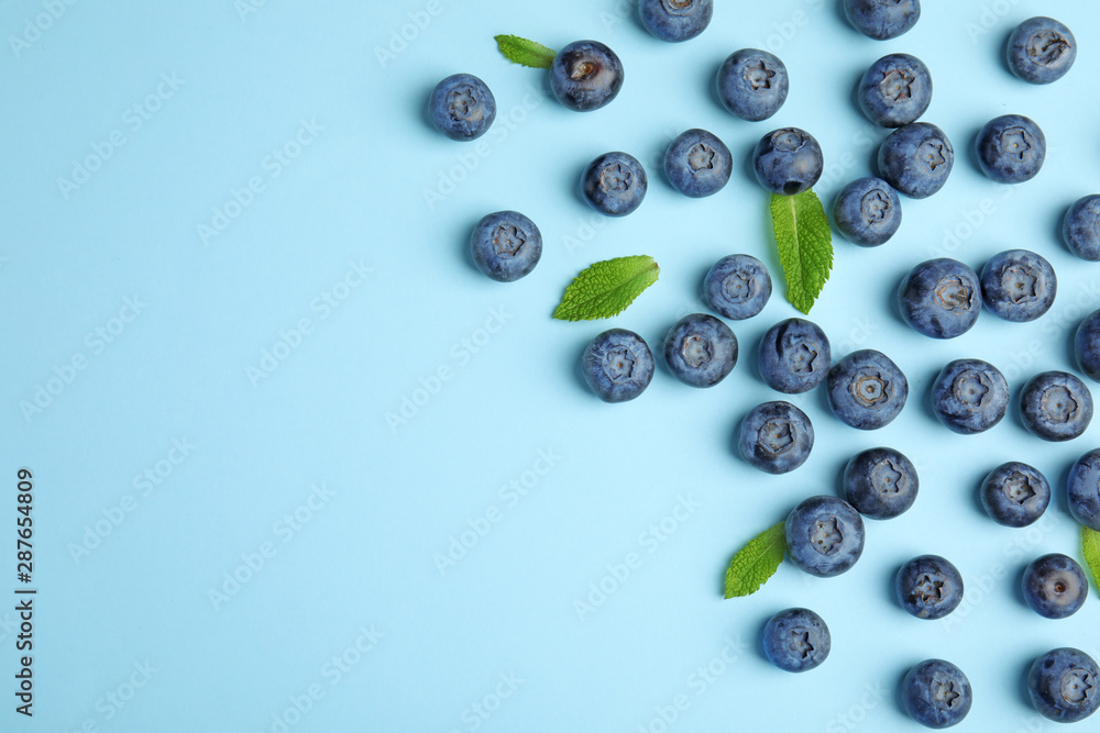 Tasty ripe blueberries and leaves on blue background, flat lay with space for text Tasty ripe blueberries and leaves on blue background, flat lay with space for text