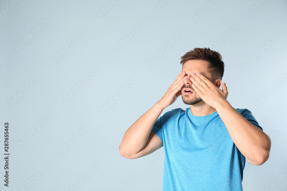 Young man being blinded on grey background, space for text Young man being blinded on grey background, space for text