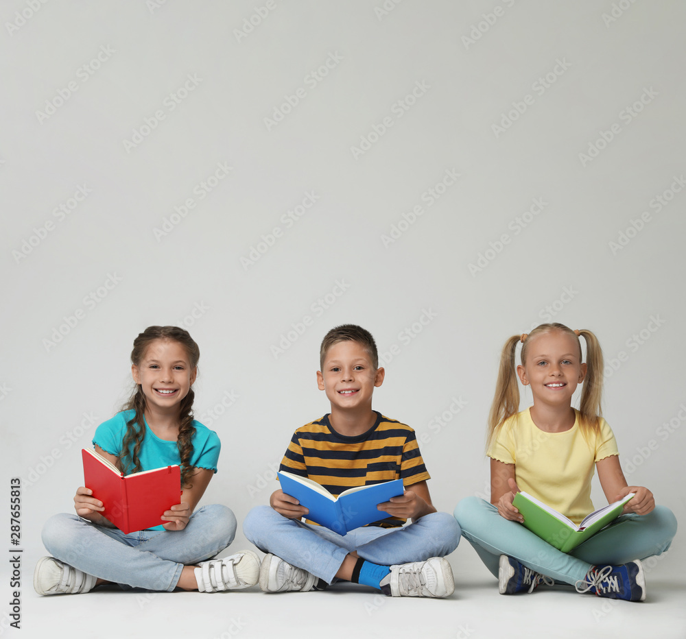 Little children reading books on grey background Little children reading books on grey background