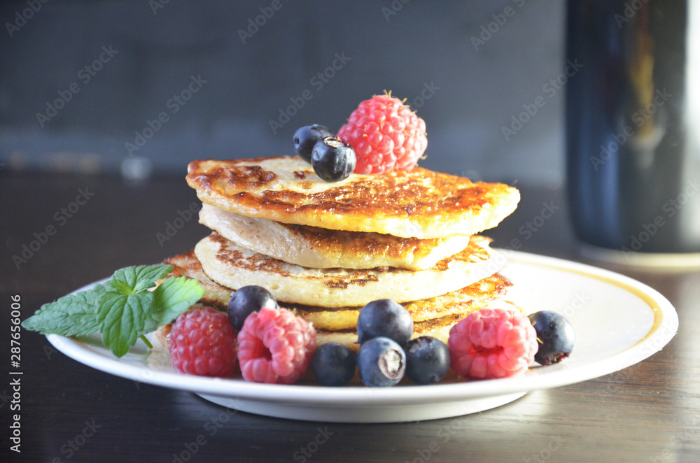 Pancakes with berries and maple syrup with raspberries and blueberries on a black background Pancakes with berries and maple syrup with raspberries and blueberries on a black background