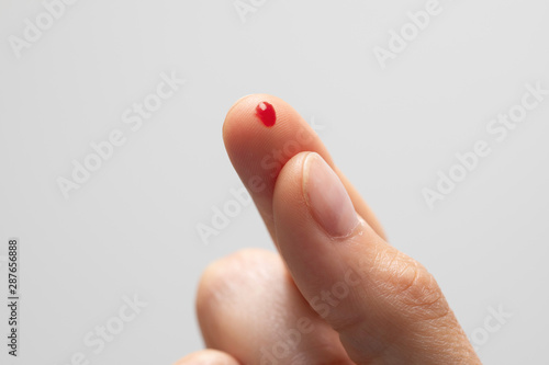 Obraz na plátne Hypoglycemia prevention as a diabetic person is seen closeup with pierced finger, small drop of blood on fingertip to monitor and analyze sugar levels in the body