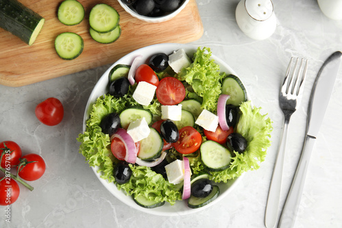Tasty fresh Greek salad on grey marble table, flat lay