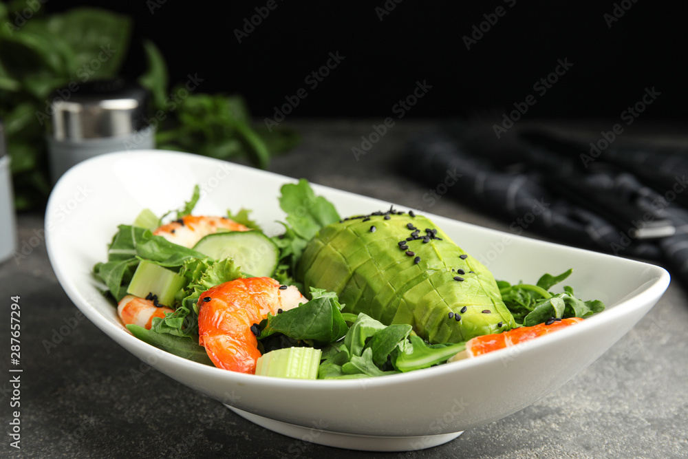 Delicious avocado salad with shrimps in bowl on grey table Delicious avocado salad with shrimps in bowl on grey table