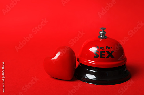 Sex bell and heart on red background. Space for text