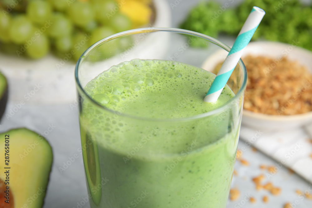 Glass of tasty avocado smoothie with straw on table, closeup Glass of tasty avocado smoothie with straw on table, closeup