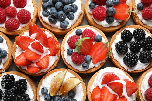 Many different berry tarts on table, top view. Delicious pastries photo