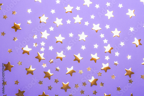 Confetti stars on violet background, flat lay. Christmas celebration