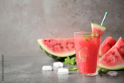 Glass of tasty refreshing drink with watermelon on grey table. Space for text