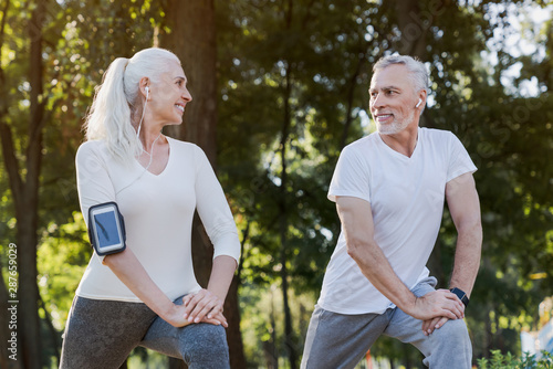 Tableau sur toile Low angle view of smiling senior couple doing warm up exercises while standing i