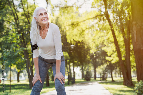 Portrait of athletic mature woman resting after jogging outdoors at park