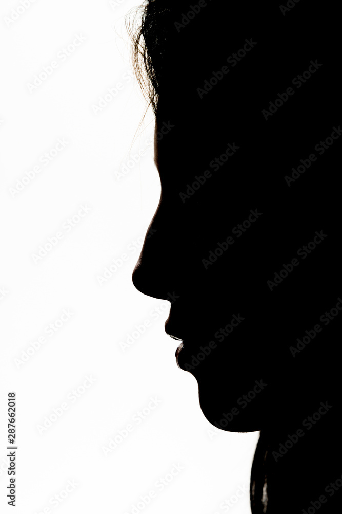 Silhouette of an attractive young girl in front of a white seamless.