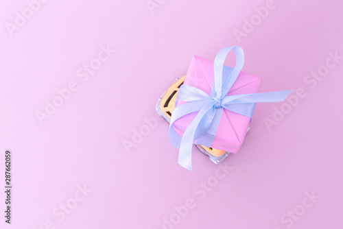 SOCHI, RUSSIA - AUGUST 05, 2019: Retro toy car hippie van delivering Christmas or New Year gift on pink background. Christmas holiday celebration and new year background concept, copy space