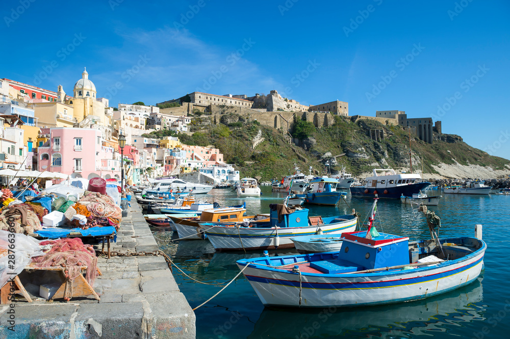 Bright morning view of the picturesque Mediterranean village of Marina Corricella with brightly colored boats moored in the foreground on the island of Procida, Italy