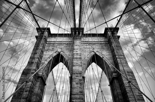 Scenic view of the architectural details of the Brooklyn Bridge in New York City in dramatic black and white monochrome under moody overcast skies