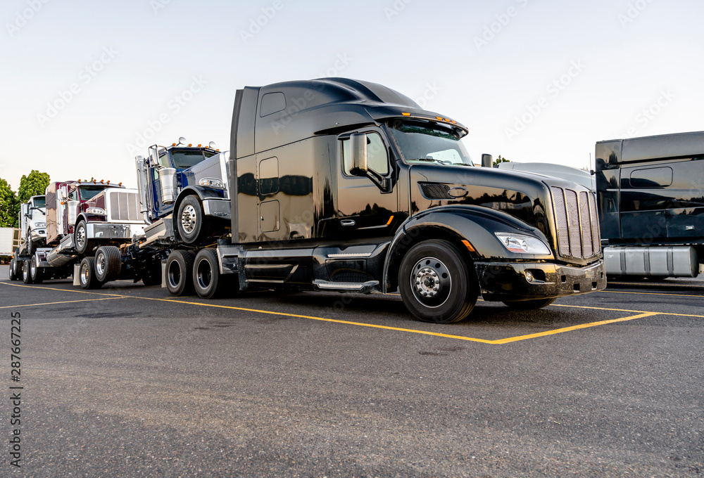 Black big rig powerful semi truck transporting coupled another semi tractors Black big rig powerful semi truck transporting coupled another semi tractors