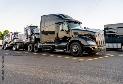 Black big rig powerful semi truck transporting coupled another semi tractors