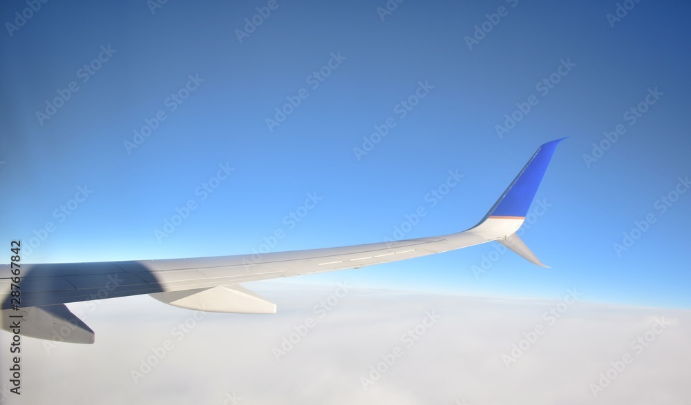 Fototapeta premium Wing of an airplane flying above the clouds