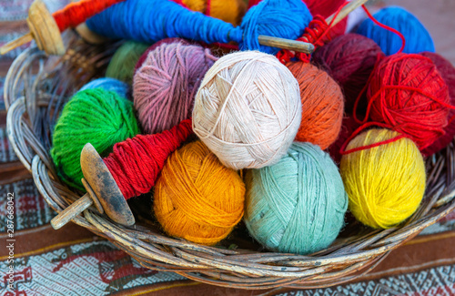 Basket with colorful alpaca wool yarn balls and spinning spindles in a textile production center in Cusco, Peru.