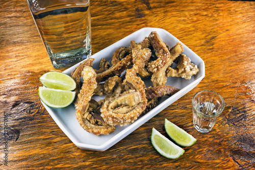 Traditional Brazilian recipe for pork crackling called pork torresmo. Traditional Brazilian food, fried and crispy pork accompanied by lemon and cachaça. photo