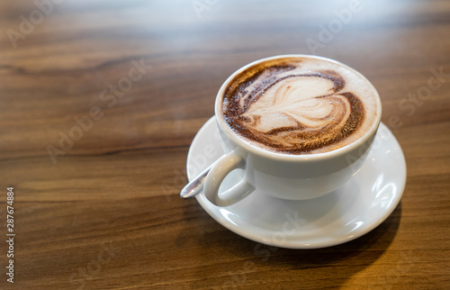 Hot coffee cappuccino latte spiral foam on dark wooden background