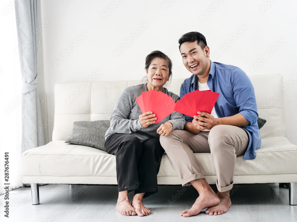 Happy Asian mother give red envelopes containing cash to her son for Chinese New Year concept. Happy Asian mother give red envelopes containing cash to her son for Chinese New Year concept.