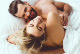top view of happy woman embracing cheerful boyfriend while lying in bed