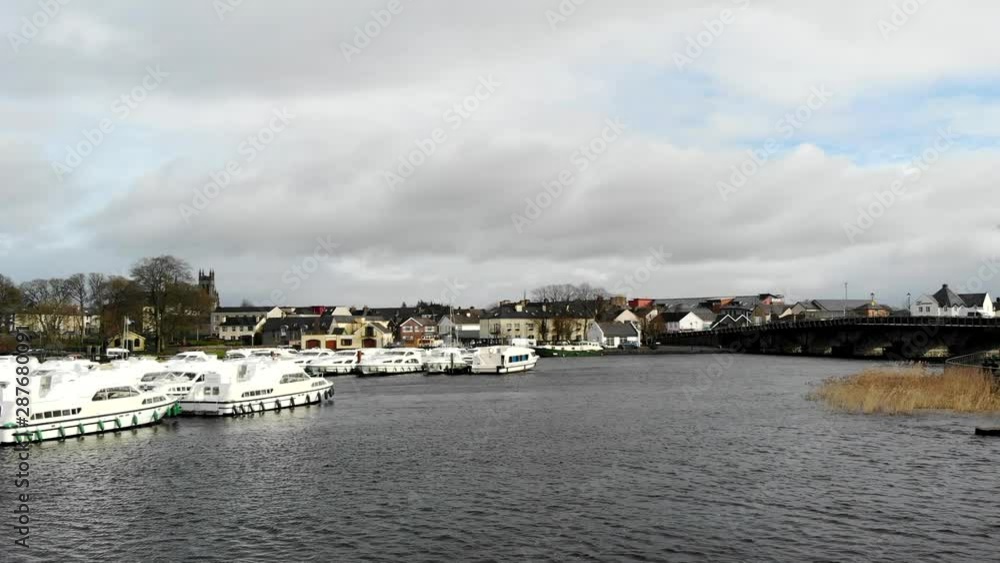 Aerial - Lakeside view in a small town. Nearby the residential area and the park with sidewalk. Bridge mainroad with traffic passing by. Aerial - Lakeside view in a small town. Nearby the residential area and the park with sidewalk. Bridge mainroad with traffic passing by.