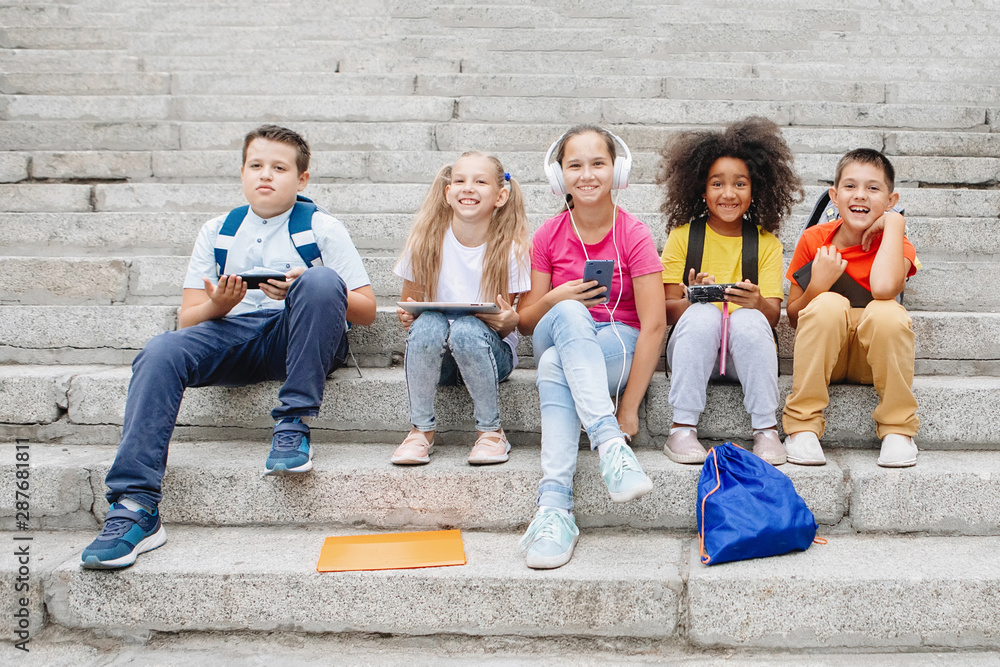 Obraz premium Group of school kids sitting on school steps