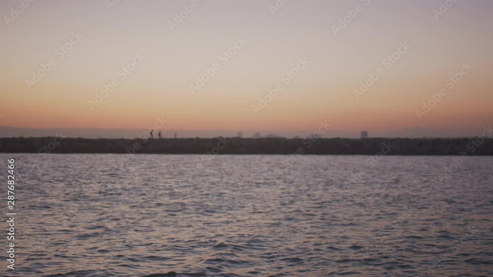 People walking on the other side of canal at sunset. People walking on the other side of canal at sunset.