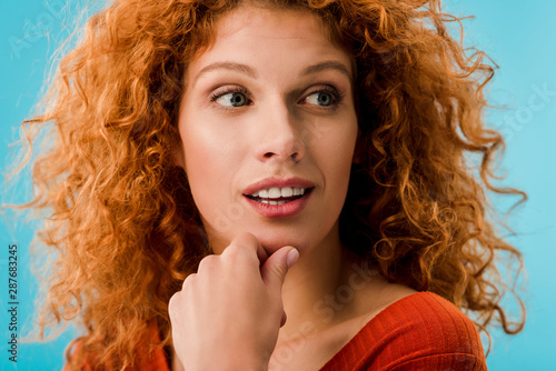 portrait of pensive redhead woman isolated on blue