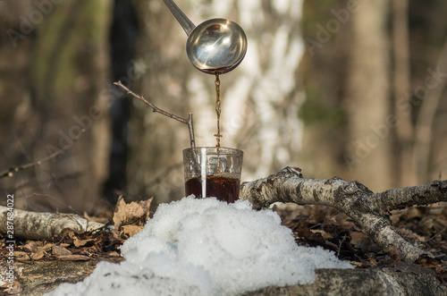 Pouring syrup from birch sap into a glass.