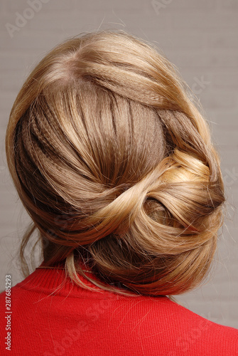 Female hairstyle bun on the head of a blonde girl back view.