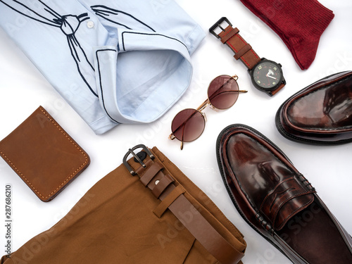 Creative fashion design for men casual clothing set isolated on white background include brown loafer shoes, yellow pants, blue shirt, watch, sunglasses, red sock and belt. top view