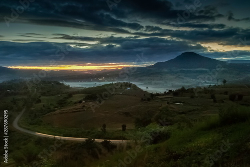 Mountain view morning above long road with forest, top hill and rainy sky background, sunrise with rain storm at Khao Takhian (takian) Ngo, Khao Kho, Phetchabun, Thailand. photo