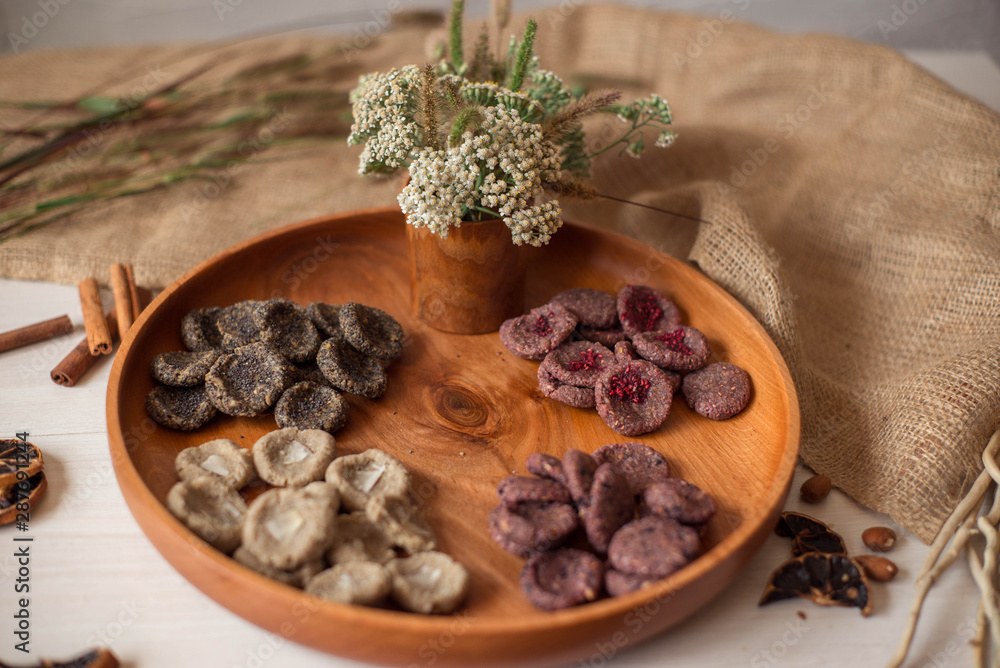 Assortment of sweets without sugar and gluten on a wooden dish. Dessert made from healthy natural ingredients. Beautiful composition of healthy diet candies and flowers