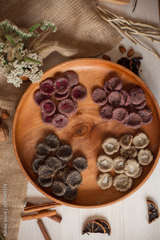 Fototapeta premium Assortment of sweets without sugar and gluten on a wooden dish. Dessert made from healthy natural ingredients. Beautiful composition of healthy diet candies and flowers