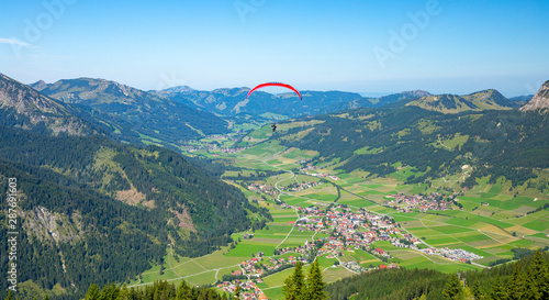Red paraglider over valley in Austrias mountains