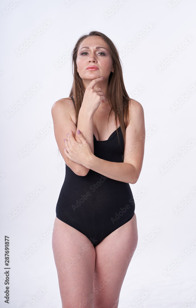 Beautiful girl in swimsuit posing against grey white background. Well-groomed skin. Sexy attire . Beautiful girl in swimsuit posing against grey white background. Well-groomed skin. Sexy attire .