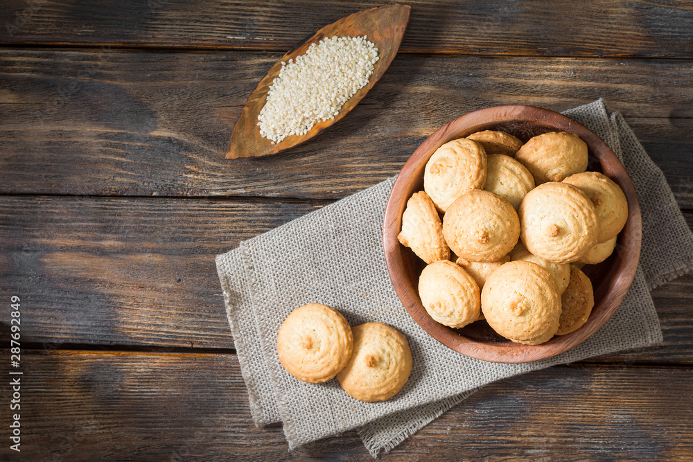 Fototapeta premium Sesame biscuit in a wooden bowl on a wooden posthole. Rustic style