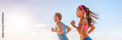 Obraz na plátně Fitness runners couple doing running exercise run at beach sunset banner panorama