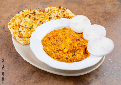 Indian Vegetarian Cuisine Special Sweet And Spicy Paneer Pasanda or Stuffed Paneer Curry, Delicacy Consisting of Stuffed Paneer with Rich Creamy Gravy Served With Garlic Naan on Vintage Background