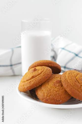 Milk glass and biscuit cookies with kitchen cloth on light background