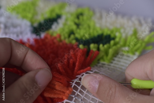 Working on a rug using latch hook technique