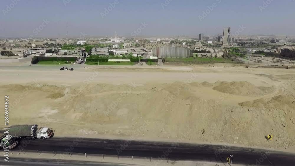 An aerial view of a city and a highway having buildings, roads, houses, parks near a site where development work is going on. An aerial view of a city and a highway having buildings, roads, houses, parks near a site where development work is going on.