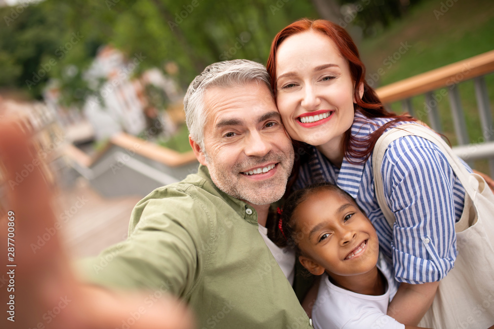 Parents and daughter smiling broadly while posing for photo Parents and daughter smiling broadly while posing for photo