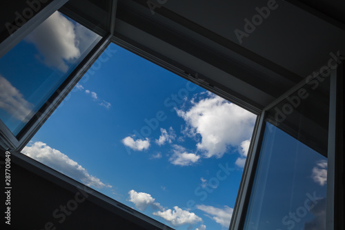An open window overlooking the urban landscape on a sunny cloud day