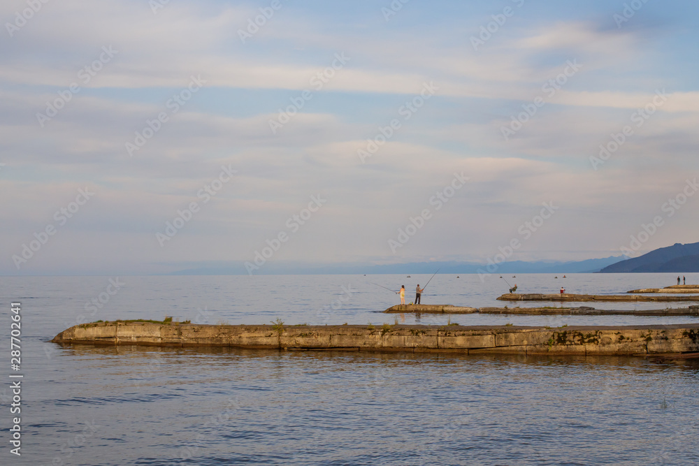 Lake Baikal. On breakwaters, fishermen catch fish with fishing rods.